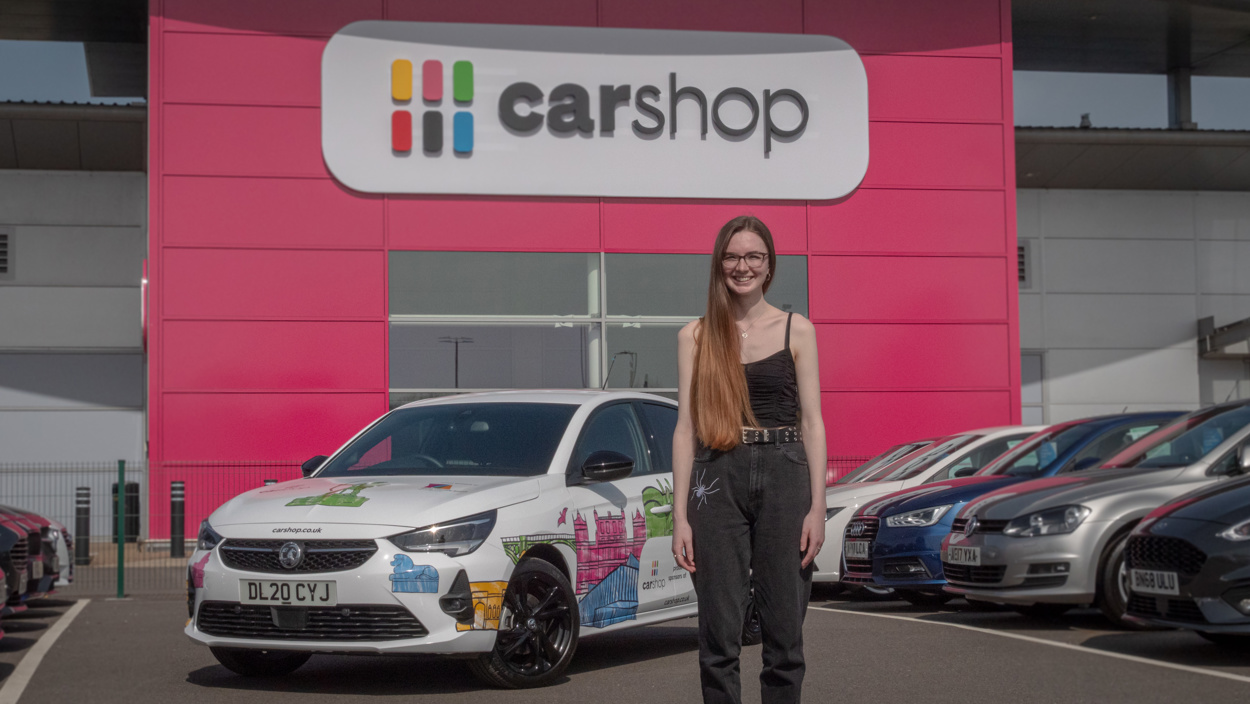 Illustrator Kate Sharp in front of the car wrap that she designed