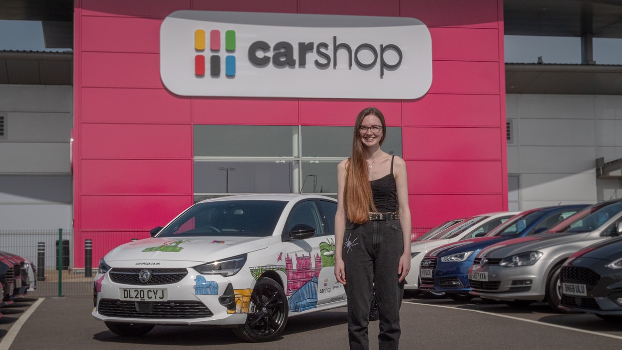 Illustrator Kate Sharp in front of the car wrap that she designed
